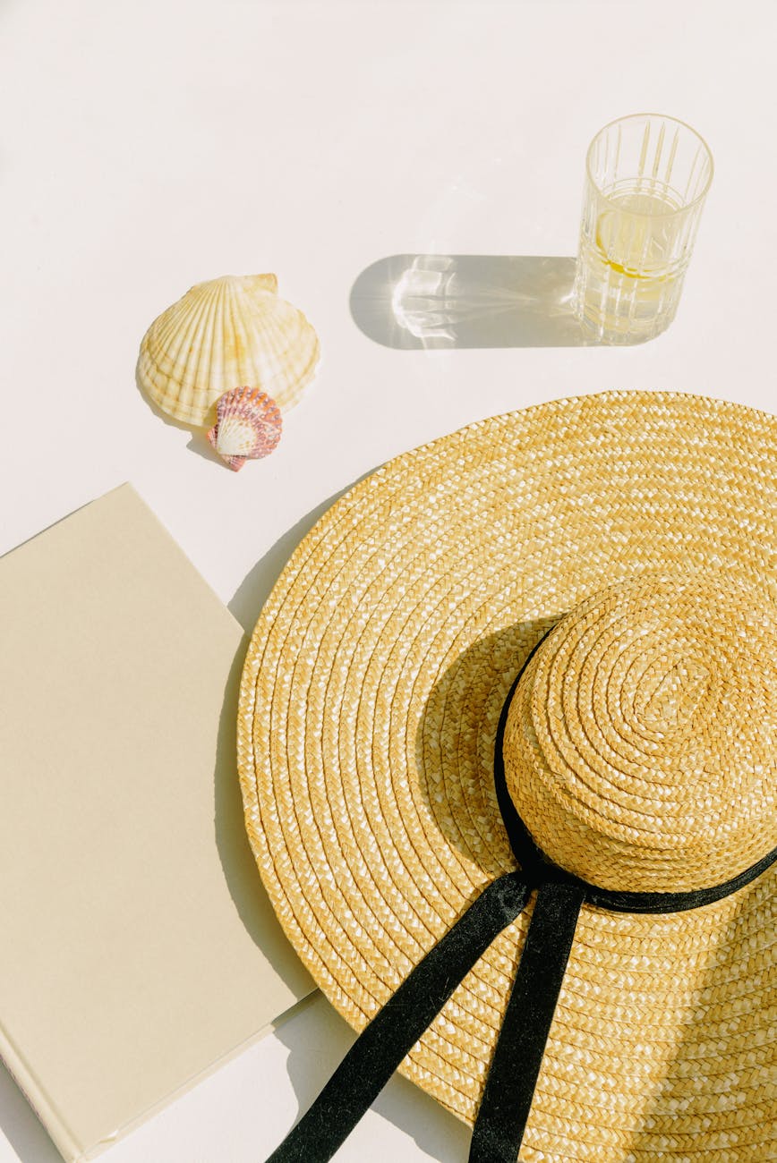 close up shot of sun hat drinking glass and a book