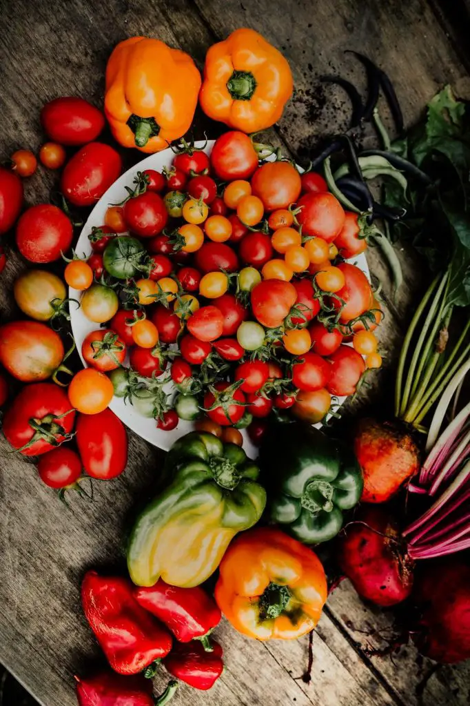 close up shot of tomatoes and peppers on a wooden surface